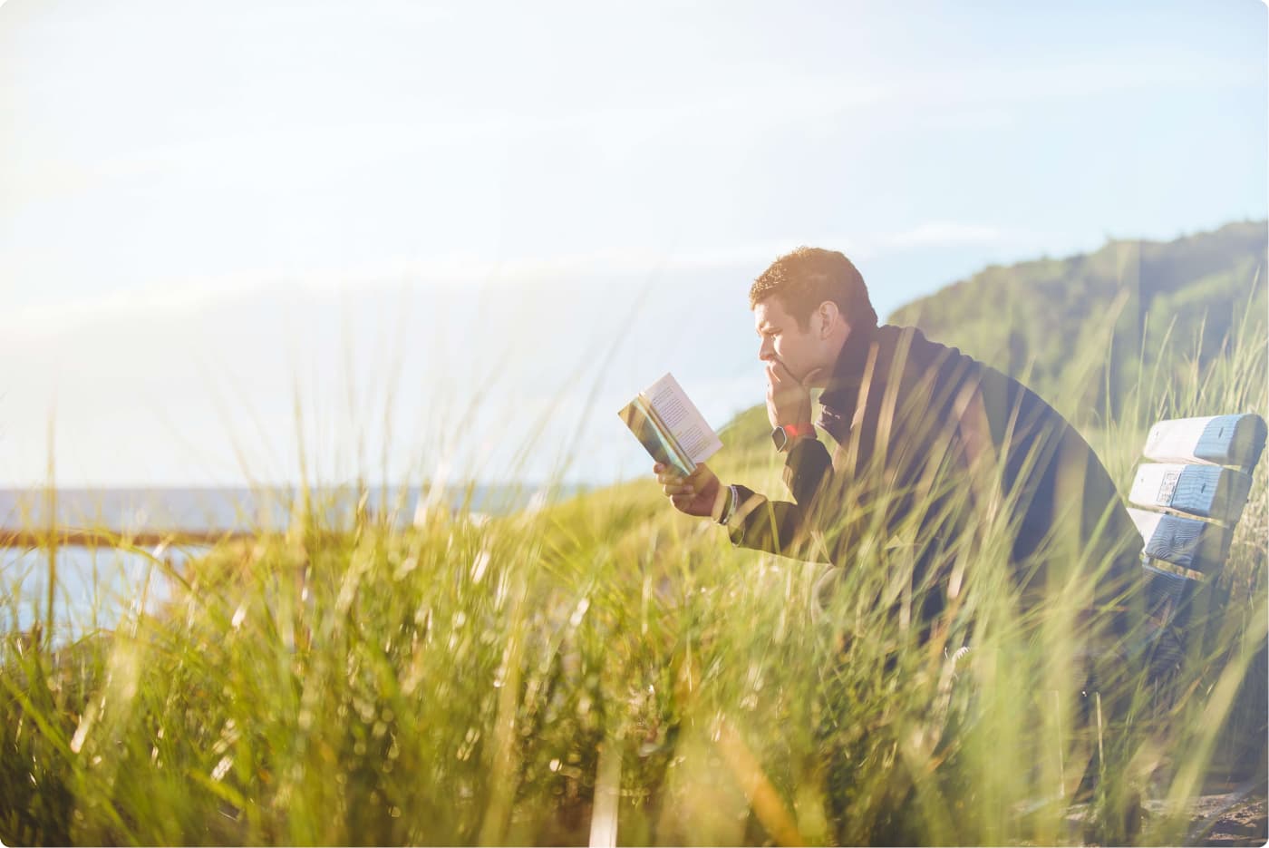 Male reading book under sun